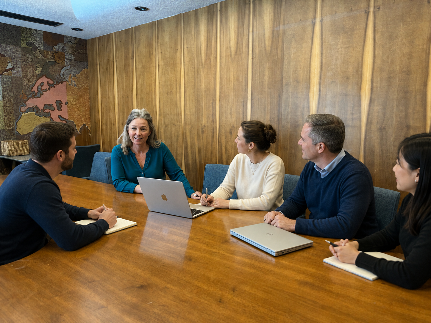 Janelle leading a team meeting around a wood conference table